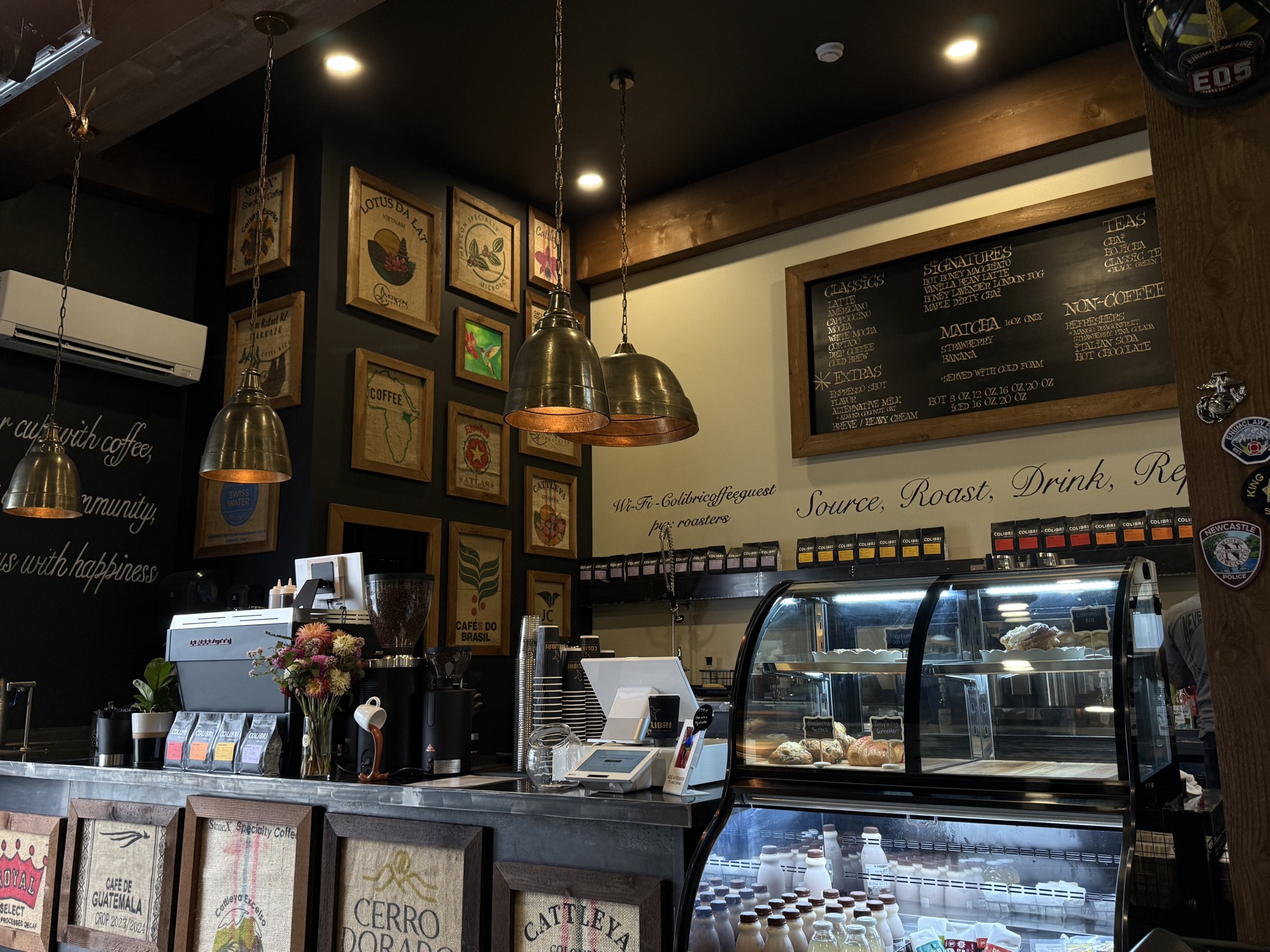 The bar — brass pendants, framed burlap coffee-sack art, the chalkboard menu in its wood frame, pastry case and espresso machine