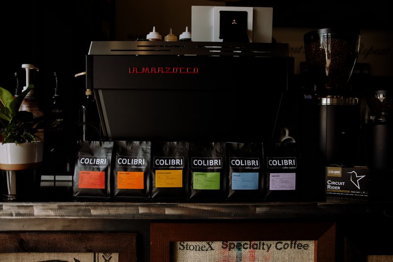 All six roasts lined up under the La Marzocco on the espresso bar, burlap coffee sacks framed below