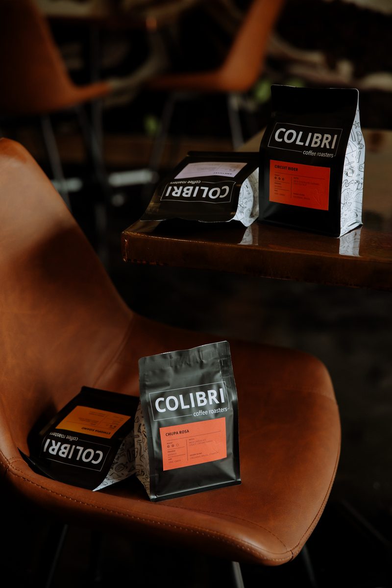 Bags of Colibri coffee set on a cognac leather chair and the table beside it