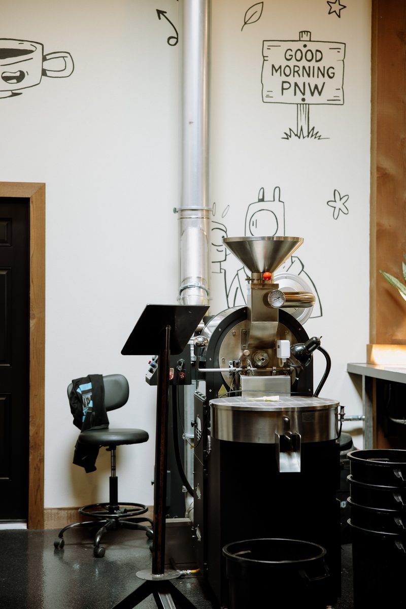 The coffee roaster in the corner of the café, below the 'Good morning PNW' doodle