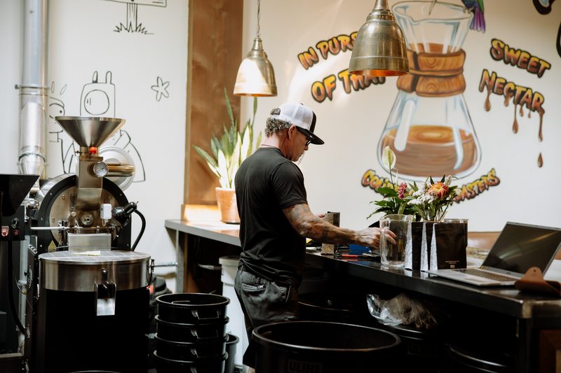 Roasting inside the café, under the 'In pursuit of that sweet nectar' mural