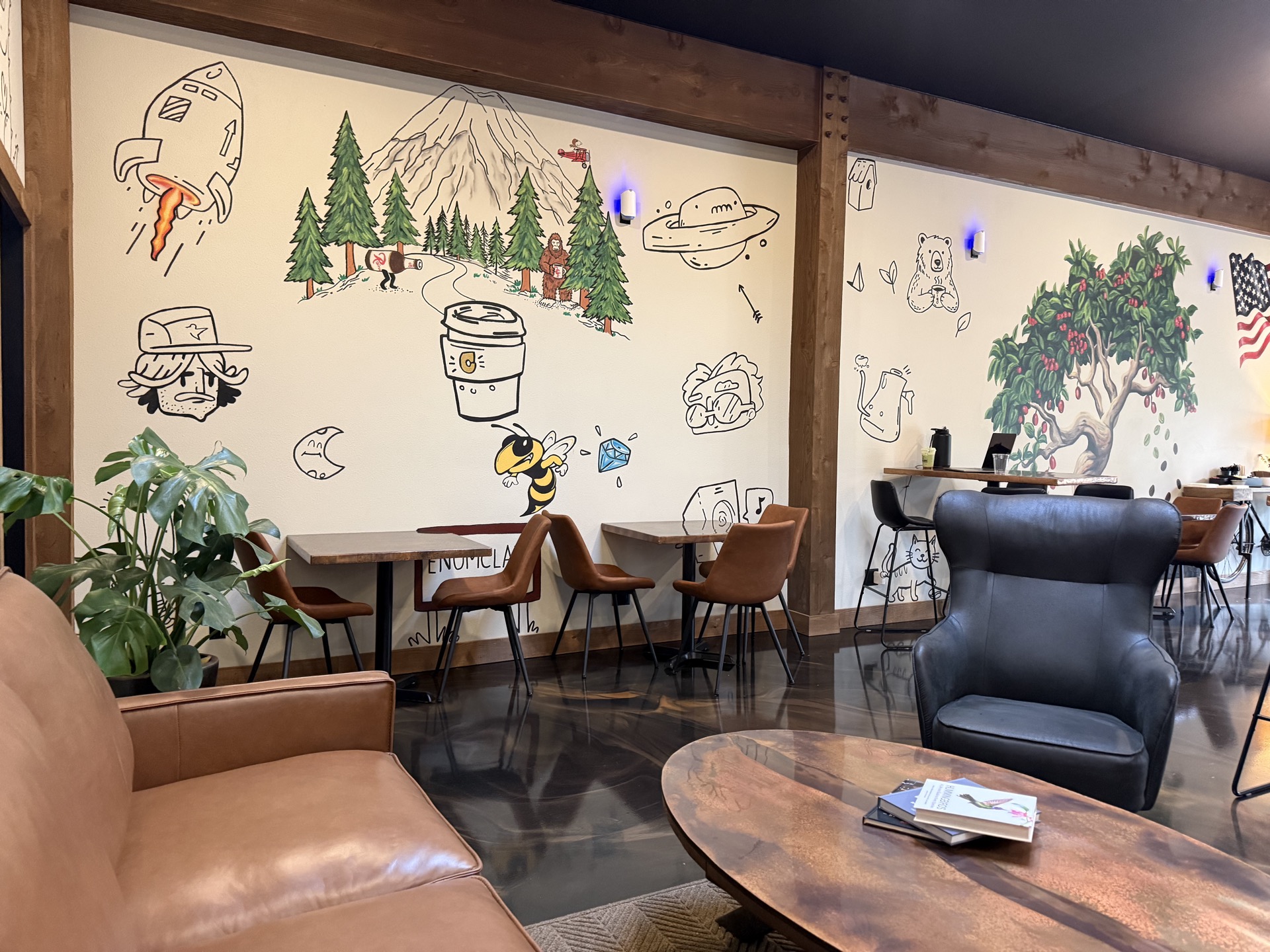 The doodle wall — hand-drawn Mt. Rainier with pines, a sasquatch holding coffee, a rocket, a bee with a diamond